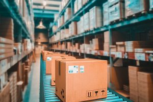 Warehouse conveyor belt with boxes, symbolizing CT Strategies’ CTPAT compliance and supply chain security services.